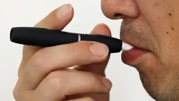 Persona usa un dispositivo IQOS. Las opiniones médicas sobre IQOS son variadas, pero este dispositivo calienta tabaco en lugar de quemarlo.