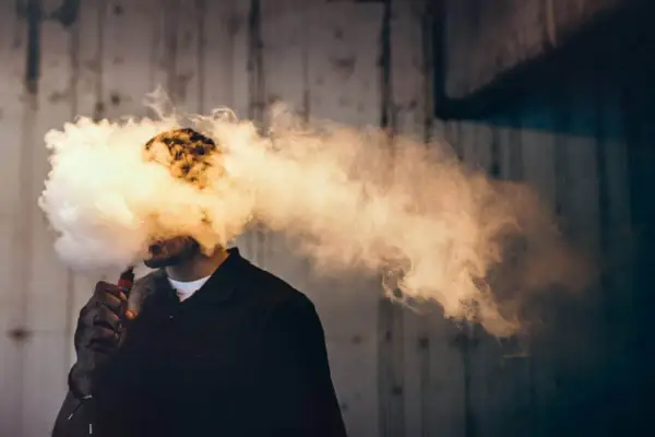 Hombre exhalando una gran nube de humo vaper, que envuelve su cabeza.