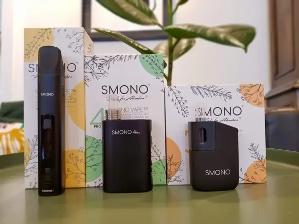 Tres vaporizadores negros de la marca Smoant, junto a sus cajas con diseños botánicos, listos para la aventura.
