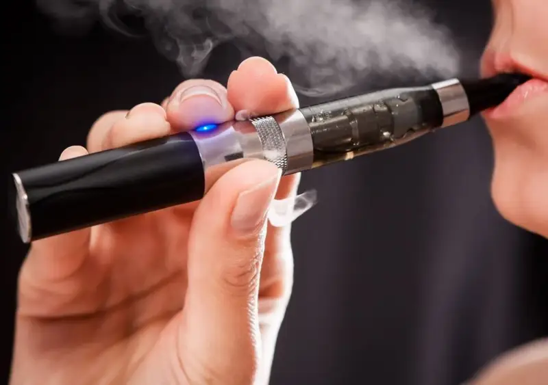 Persona usa un vaper saludable, exhalando vapor blanco.