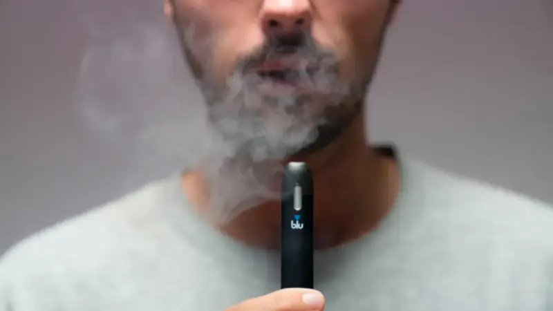 Hombre exhala humo de un vaper blu. Este vaper blu es malo para la salud.
