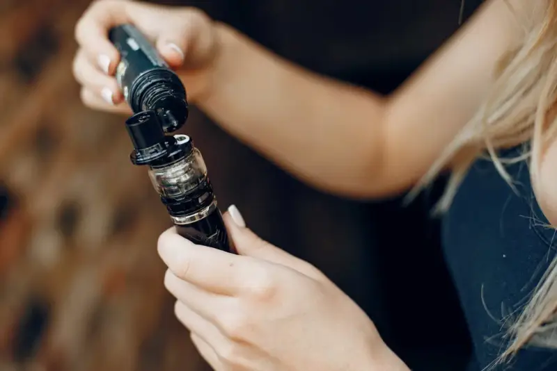 Manos rellenando un cigarrillo electrónico, mostrando las tecnologías sub ohm para una experiencia de vapeo intensa.